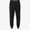 Calvin Klein Reimagined Logo-band Relaxed-fit Mid-rise Cotton-recycled Polyester Blend Jogging Bottoms 1 Calvin Klein Reimagined Logo-band Relaxed-fit Mid-rise Cotton-recycled Polyester Blend Jogging Bottoms -Sweaty Betty Store R03875729 BLACK M